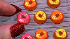 there are six donuts with different designs on them, and one is being held by someone's hand