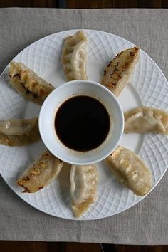 a white plate topped with dumplings next to a cup of black liquid on top of a table