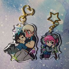 two key chains with anime characters on them, one holding the other's head