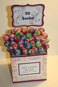 a box filled with lots of colorful candies next to a sign that says 50 sucks