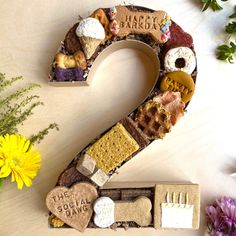 the number two made out of different types of food and sweets is displayed next to flowers