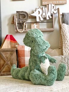 a green teddy bear sitting on top of a bed next to a wooden sign and pillow