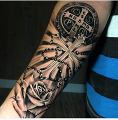 a person with a cross and rose tattoo on their arm