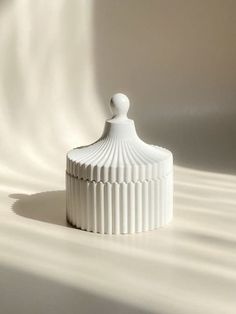 a white container sitting on top of a white floor next to a light colored wall