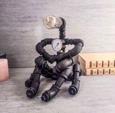 a steampunk robot sitting on the ground next to some books and a clock