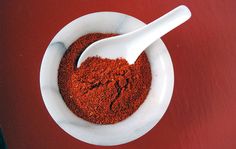 a white bowl filled with red powder and a spoon