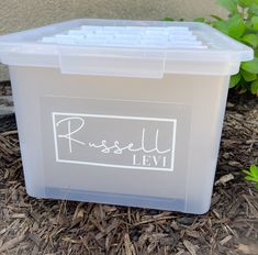 a plastic box sitting on the ground in front of some plants and dirt with words that read russell levi