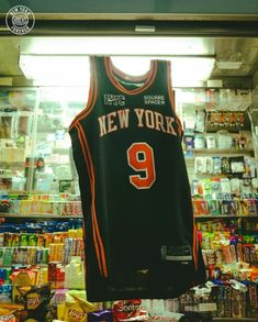 a basketball jersey hangs in front of a store display case filled with snacks and candy