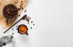 coffee beans in a bowl next to an umbrella and other items on a white surface