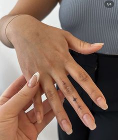 two people with their hands together holding each other's fingers and tattoos on their fingers