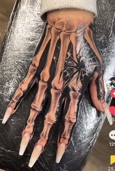 a person's hand with fake nails on it and an image of a skeleton