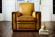 a brown leather chair sitting on top of a hard wood floor next to a white door