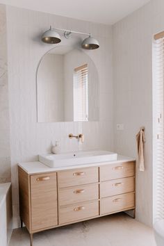 a bathroom with a sink, mirror and bathtub next to a window in it