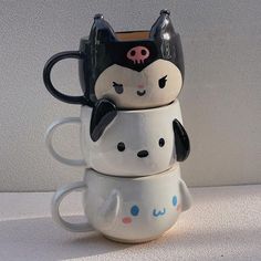 three coffee mugs stacked on top of each other with faces painted on the cups