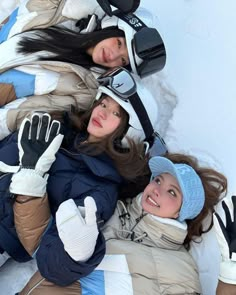 two women laying in the snow with gloves on