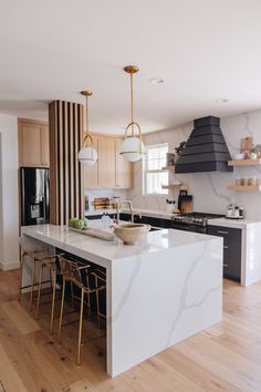 a large kitchen with an island in the middle and two pendant lights hanging from the ceiling