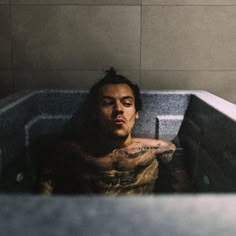 a man with tattoos sitting in a bathtub