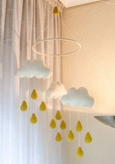 a crocheted cloud mobile hanging from the ceiling next to a window with curtains