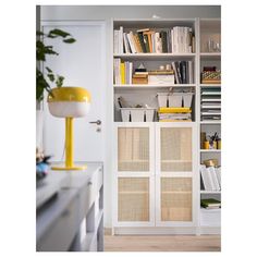 a white bookcase with yellow lamp and books