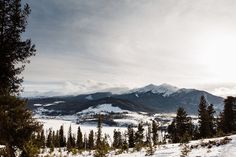 the sun shines brightly on snow covered mountains and pine trees in the foreground