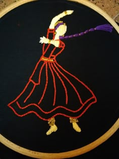 a woman in a red dress is embroidered on a black background with orange thread and yellow beads