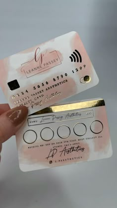 a person holding up a pink and white business card with gold foil on it's side