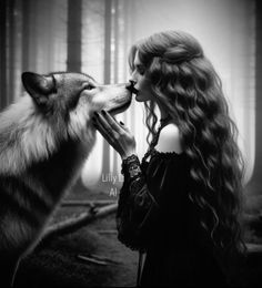 a woman with long hair kissing a wolf in front of a forest filled with trees