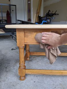 a person wiping their hands under a wooden table with a cloth on the top and underneath it