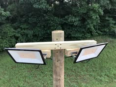 two flood lights are attached to a wooden post in the grass near some trees and bushes