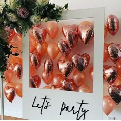 there are balloons in the shape of hearts on this party wall with flowers and greenery