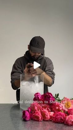 a man sitting at a table with flowers in front of him looking at his phone