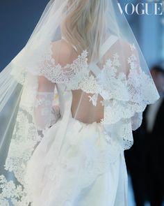 the back of a bride's wedding dress with an intricate lace and tulle veil