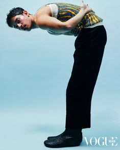 a man in black pants and white shirt is doing a handstand on a blue background