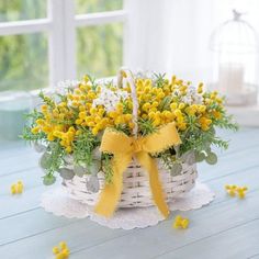 a basket filled with yellow flowers on top of a wooden table next to a window