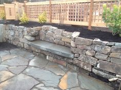 a stone bench sitting next to a wooden fence