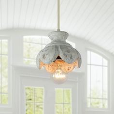 a light fixture hanging from the ceiling in a room with white walls and large windows