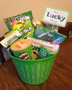 a green bucket filled with snacks on top of a wooden table next to a sign