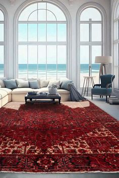 a living room filled with lots of furniture next to an ocean side window covered in large windows