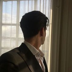 a man in a suit looking out the window