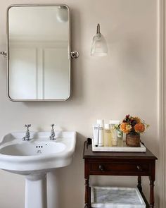 a white sink sitting next to a wooden table with a mirror on top of it