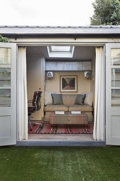 an outdoor living area with a couch and chair in the doorway to a shed style home