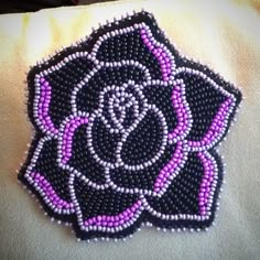 a black and purple beaded rose on a white pillow