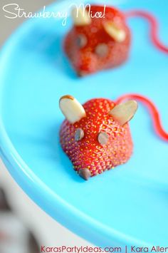 two strawberries shaped like mice sitting on a blue plate with the words strawberry mouse