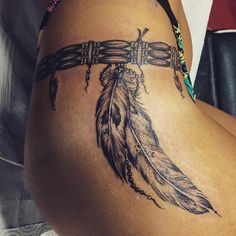 a woman's thigh with a tattoo on it and a feather attached to the leg