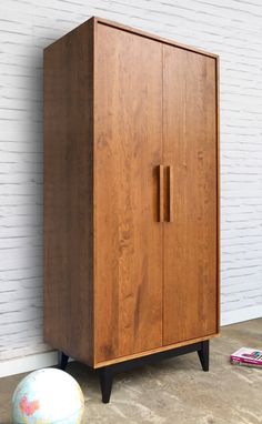 a wooden cabinet sitting next to a white brick wall with a ball on the floor