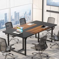 an empty conference table with chairs and a laptop on it in front of a large window