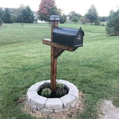 a mailbox sitting in the middle of a flower bed on top of a grass covered field