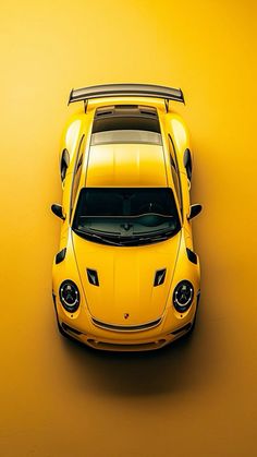 an overhead view of a yellow sports car with the hood down on a yellow background