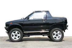 a black pick up truck parked in front of a white wall