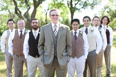 a group of men standing next to each other in front of trees wearing suits and ties